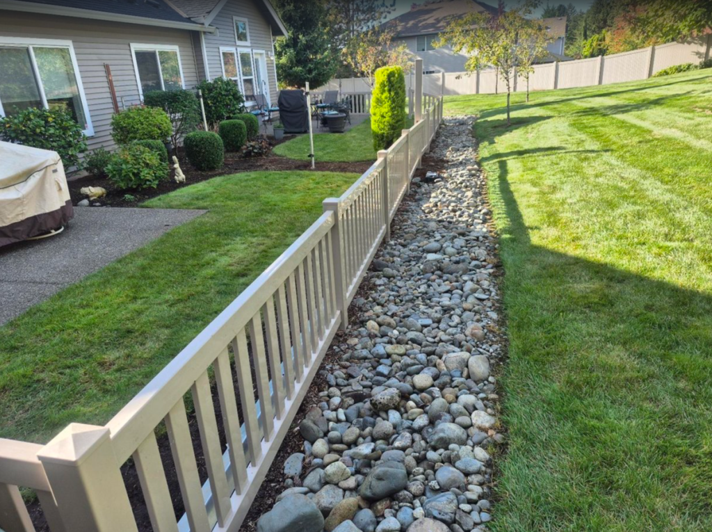 Semi-private residential fence installed beside a landscaped rock drainage bed
